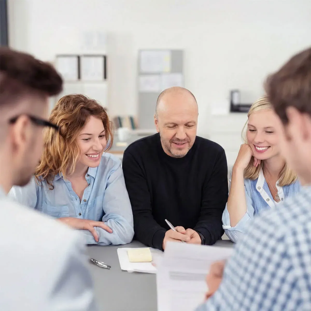 Eine Gruppe bespricht am Tisch gemeinsam Unterlagen.