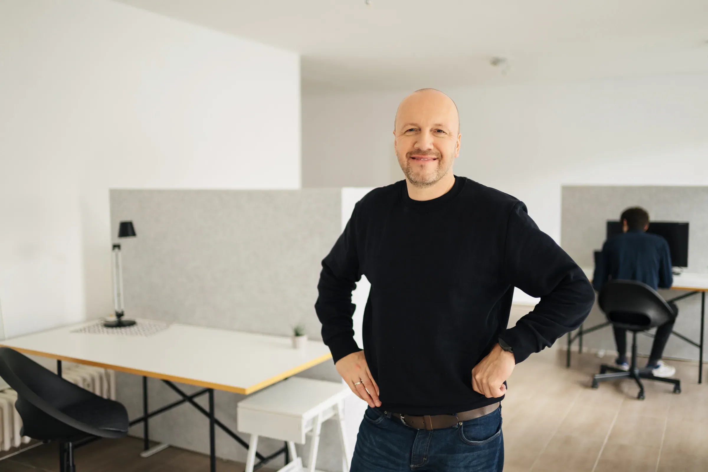 Ralf Cornesse steht im Büro und schaut in die Kamera, hinter ihm Arbeitsplätze mit Rechnern